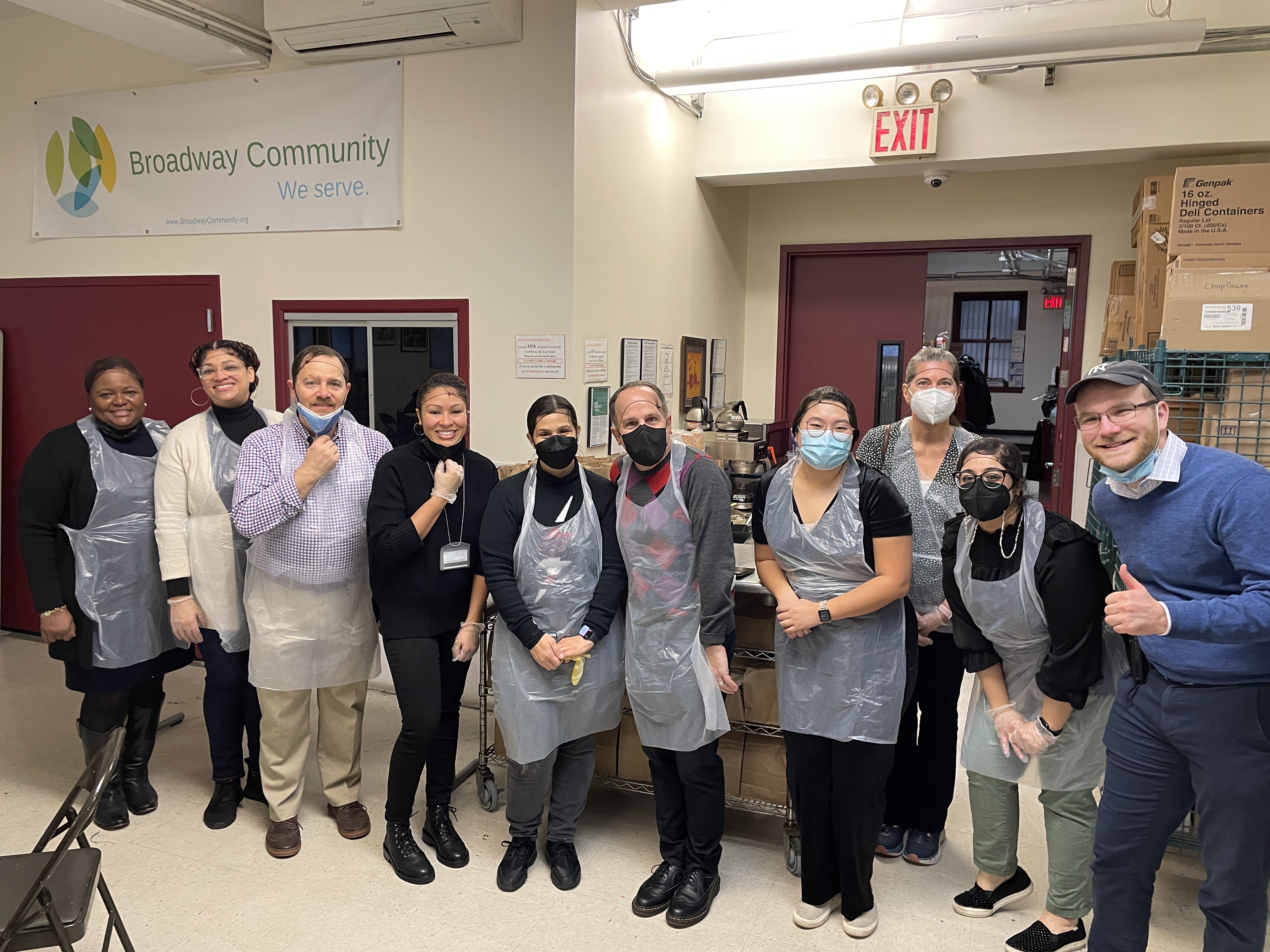 A group of folk gathered wearing hair nets, aprons, and masks. 