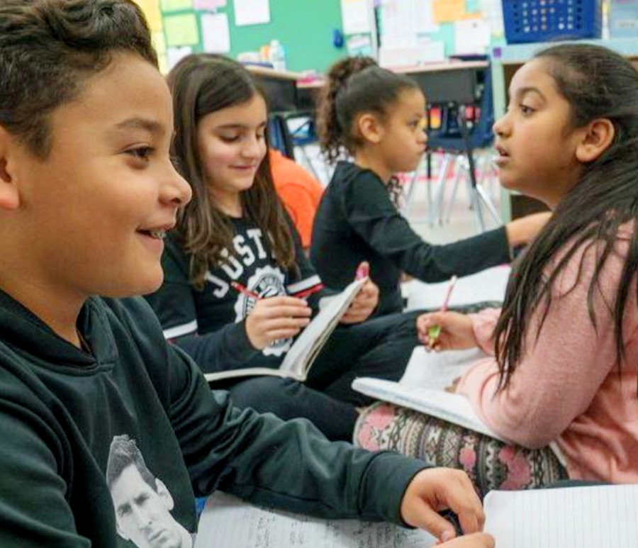 Four young students writing in notebooks