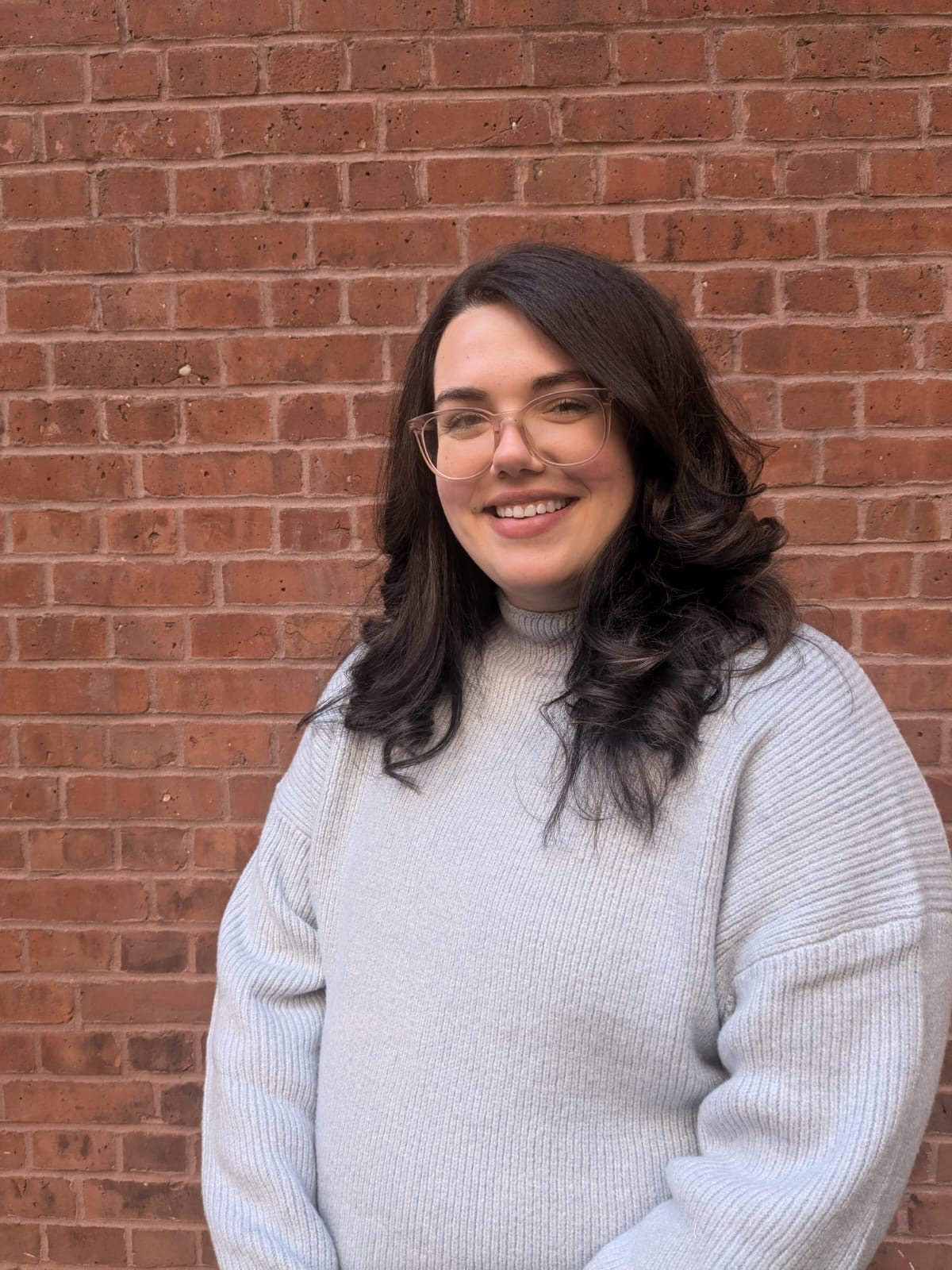 A woman standing against a brick wall