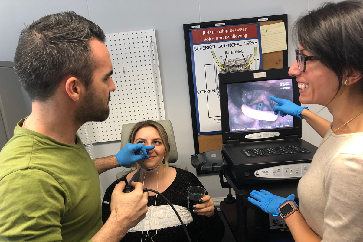 Two researchers measure upper airway disfunction using a scope in their patient