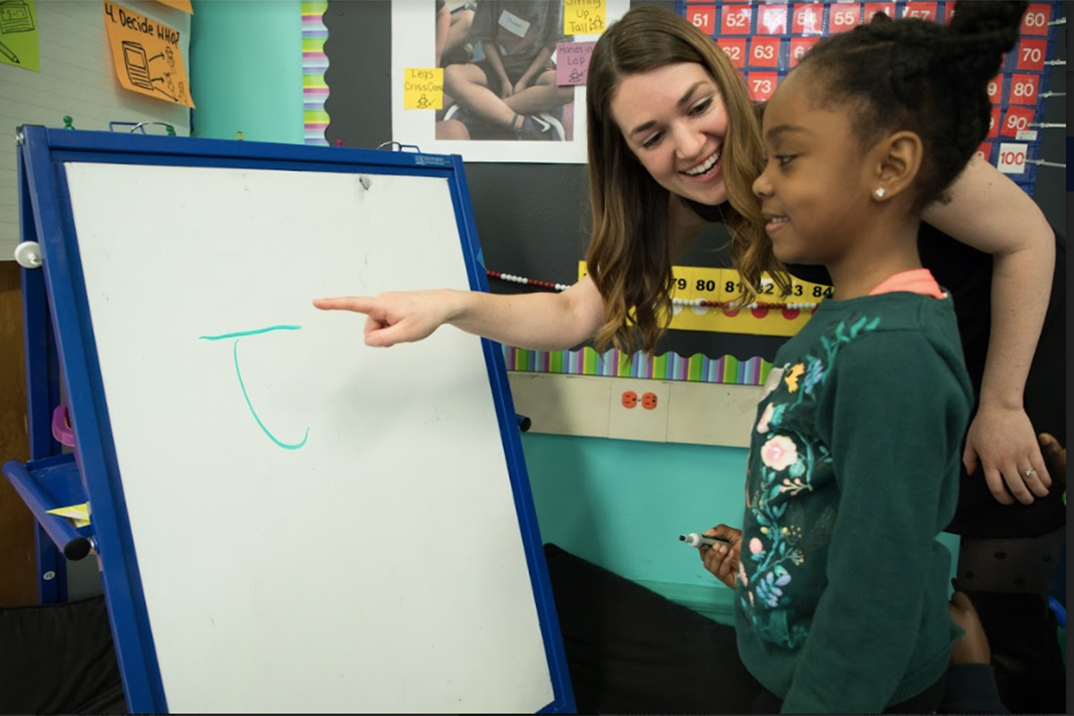 Teacher with young student at a white board.