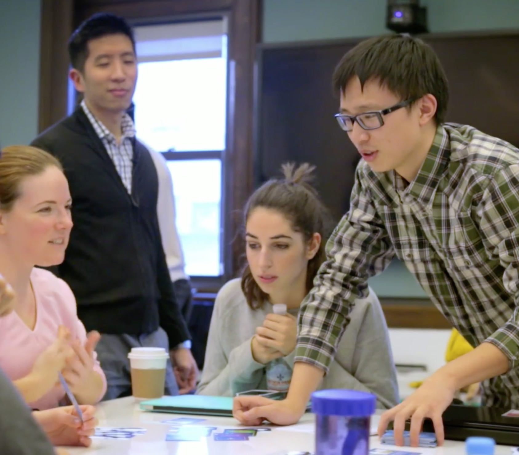 ALPHA PHASE Faculty member Joey Lee (standing, left) with members of a student project team. The teams worked with experienced researchers and mentors to critically examine their process and work.