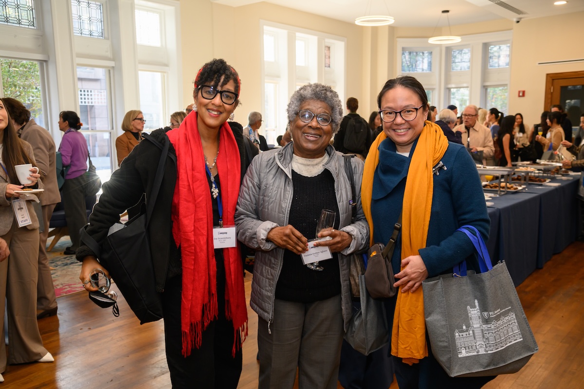 Three alumna pose and smile together in Everett Lounge