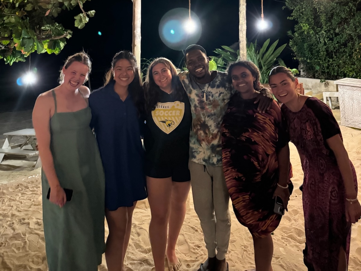 A group of people standing on the beach at night.