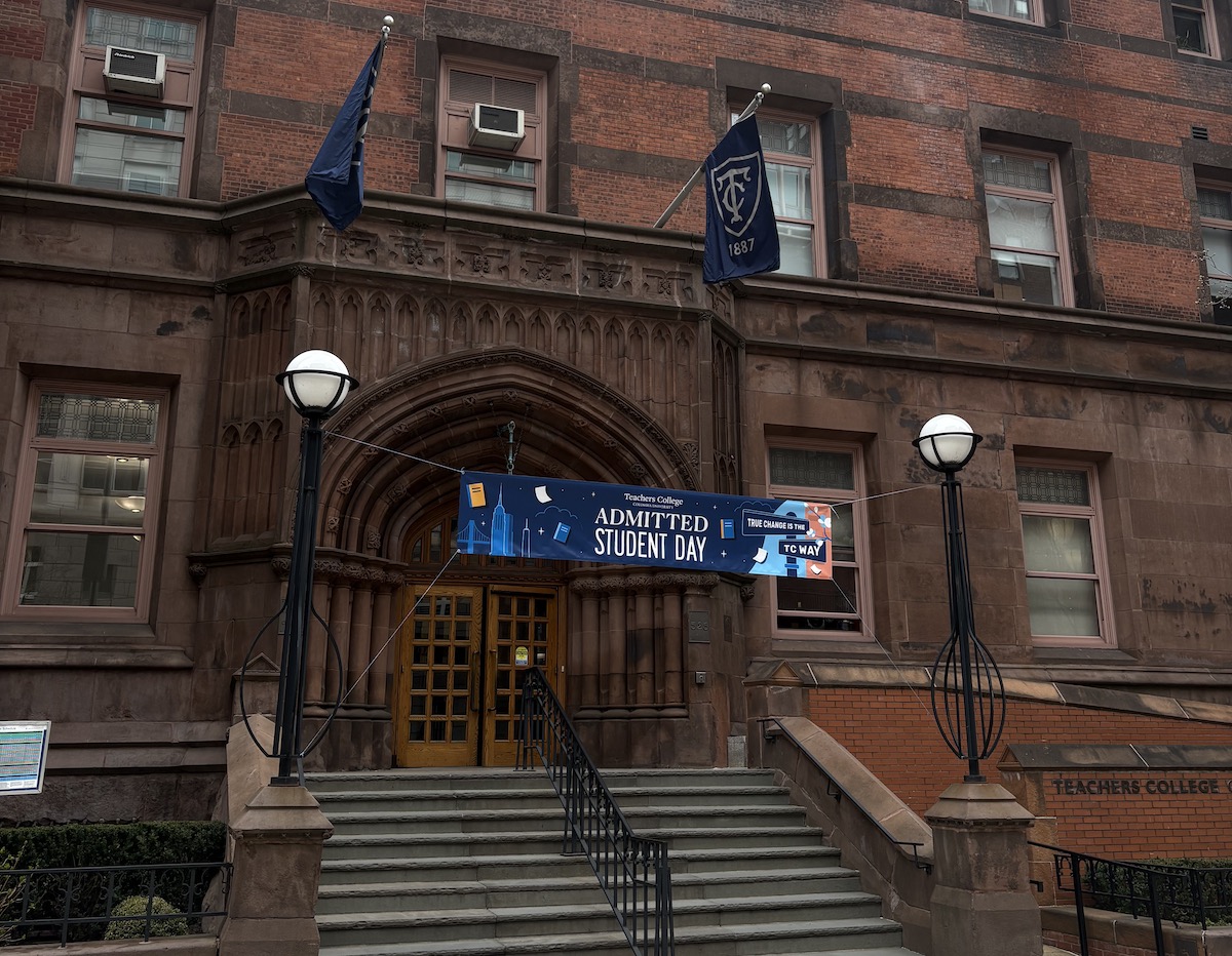 The front entrance of Teachers College. A banner hangs across the steps that reads 