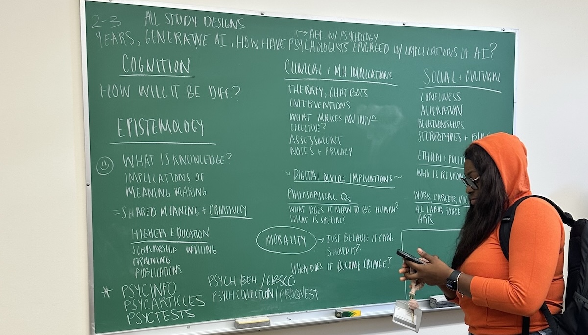 A student standing in front of a green chalkboard