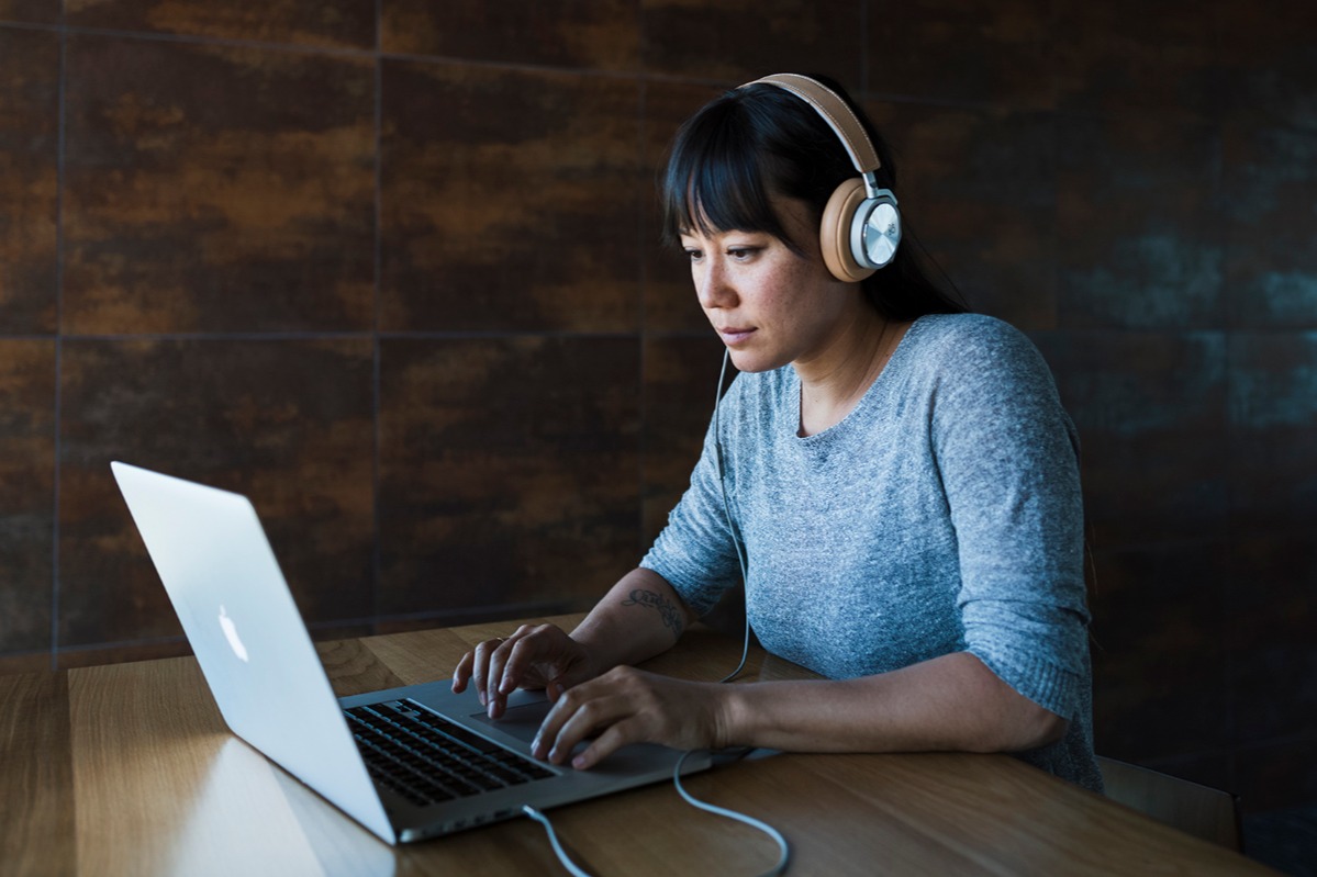 A woman using a laptop with headphones