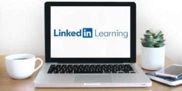 A laptop on a desk with the Linkedin Learning logo on the screen