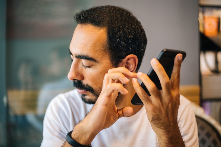 Blind man listening to prompts made by the smartphone that he's using