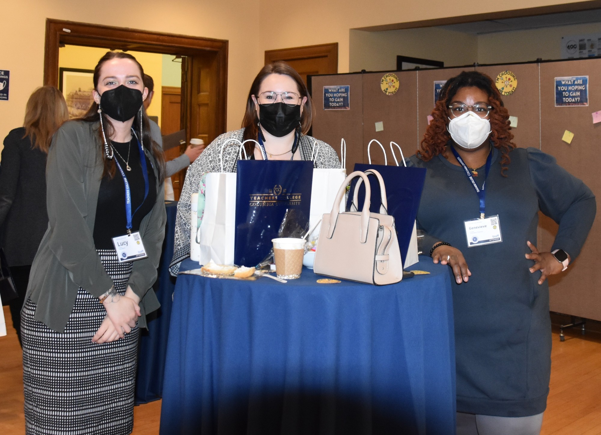 Group of 3 individuals masked around a table with prepackaged food bags. 