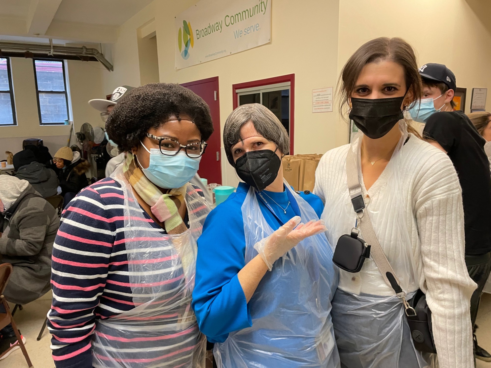 Group of three people masked, but smiling, and wearing hair nets.
