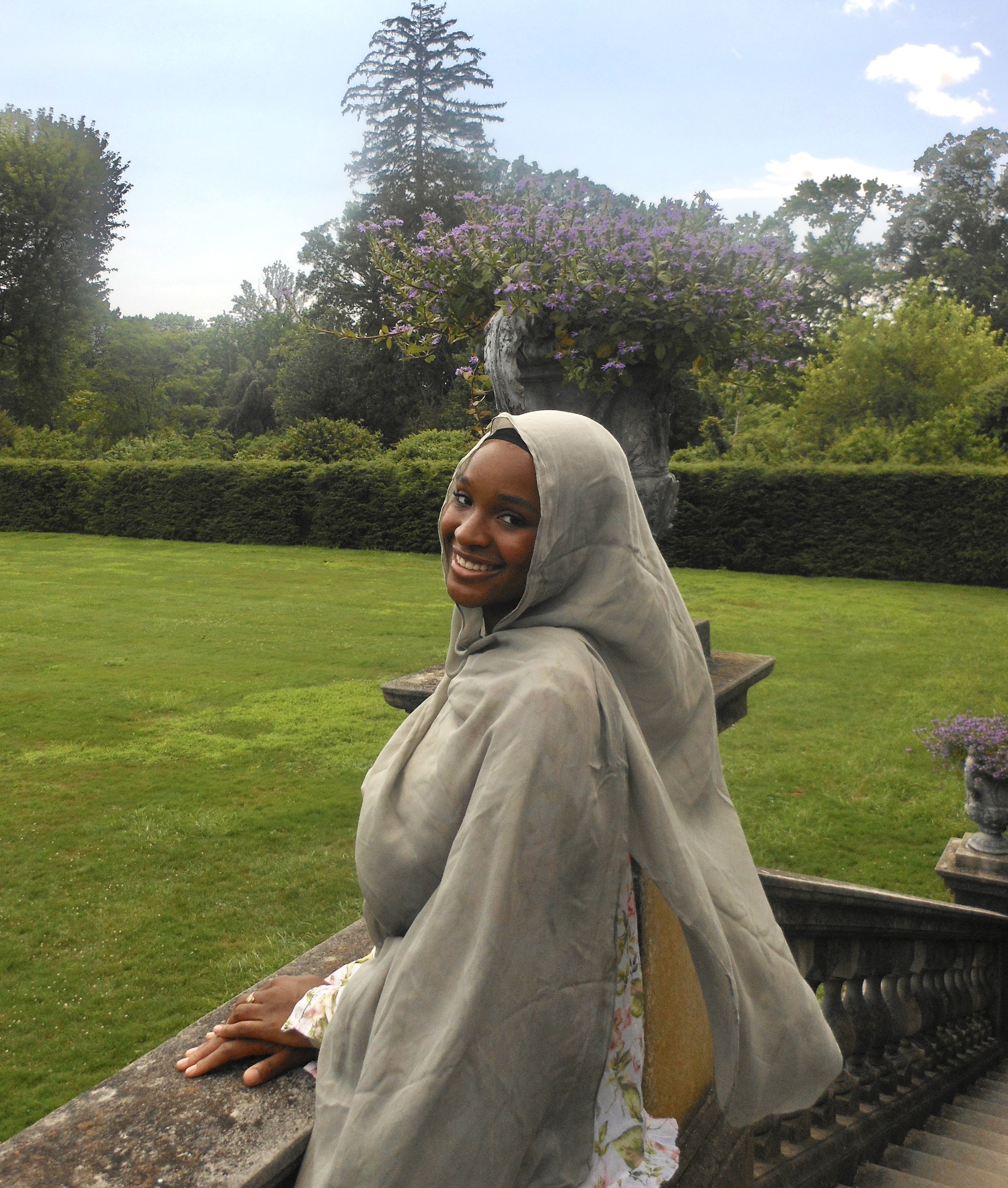 Photo of a student looking over her shoulder at the camera with green grass in the background