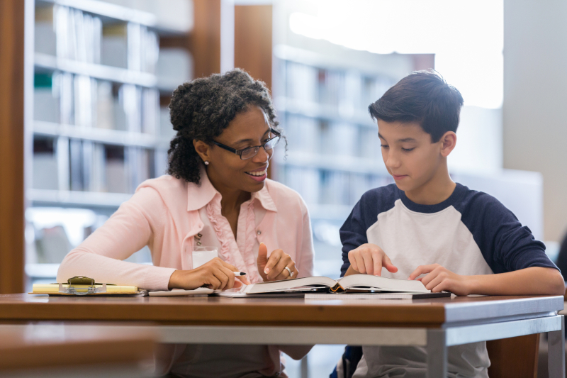 Teacher in class with student reviewing assignment