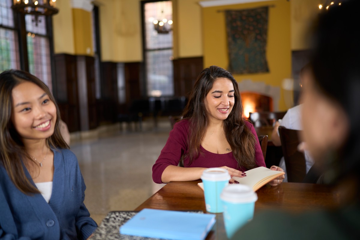 Two students sitting at a table in Grace Dodge Dining Hall. There are books and coffee cups sitting in front of them.