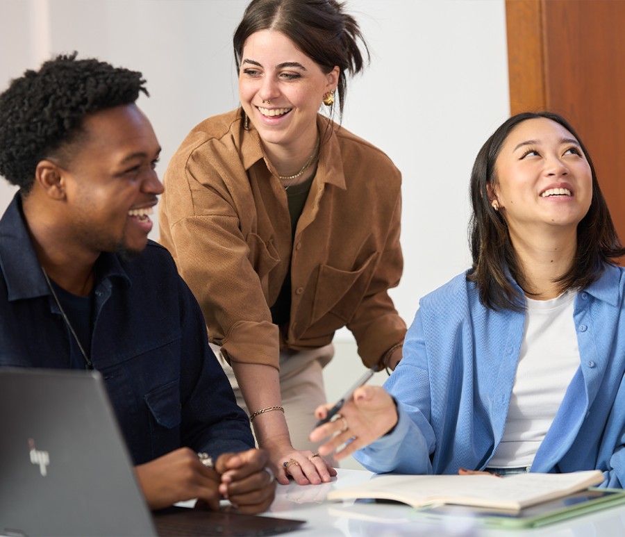 Three students smiling in a classroom
