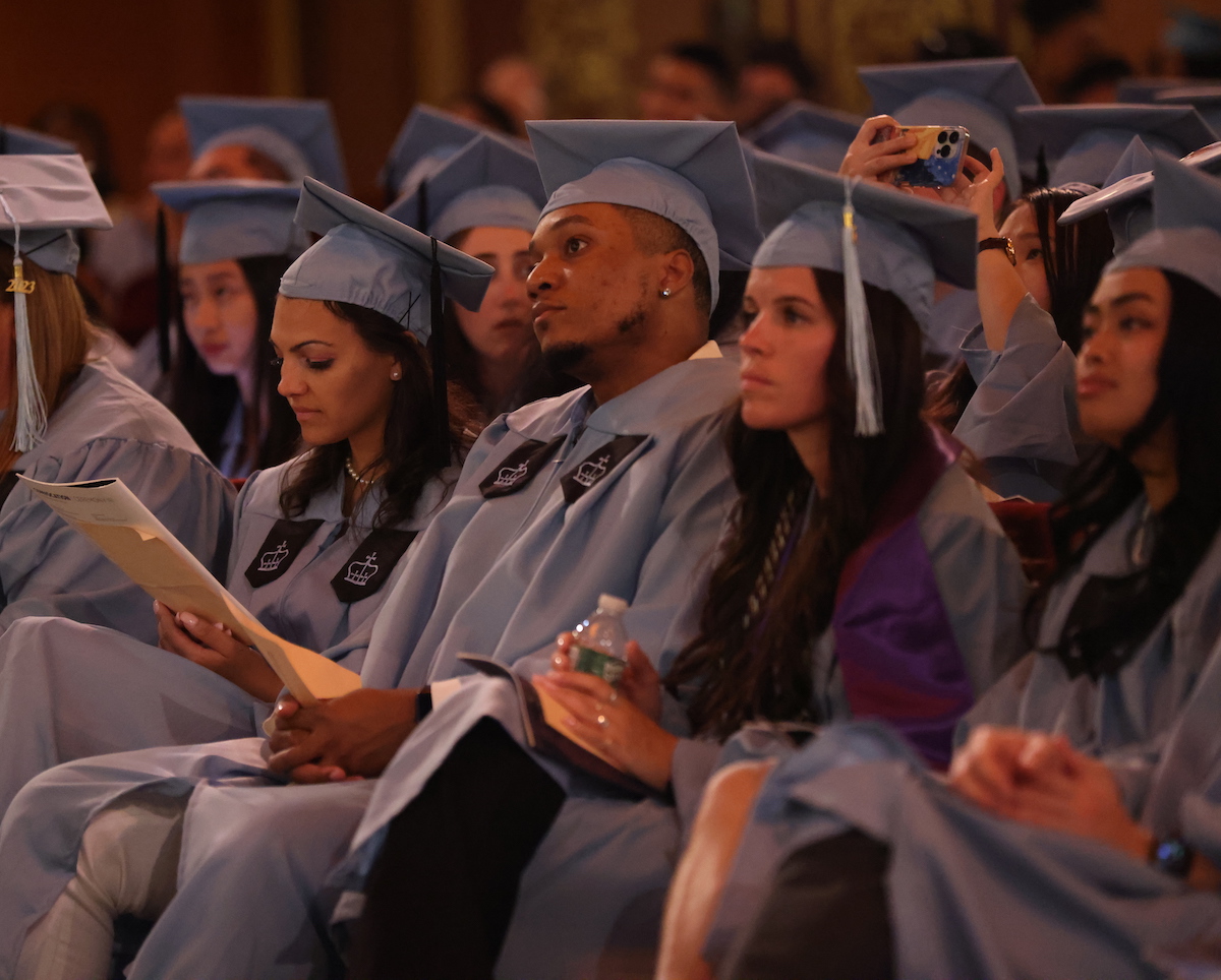 Graduates wearing their regalia sit in the audience at commencement