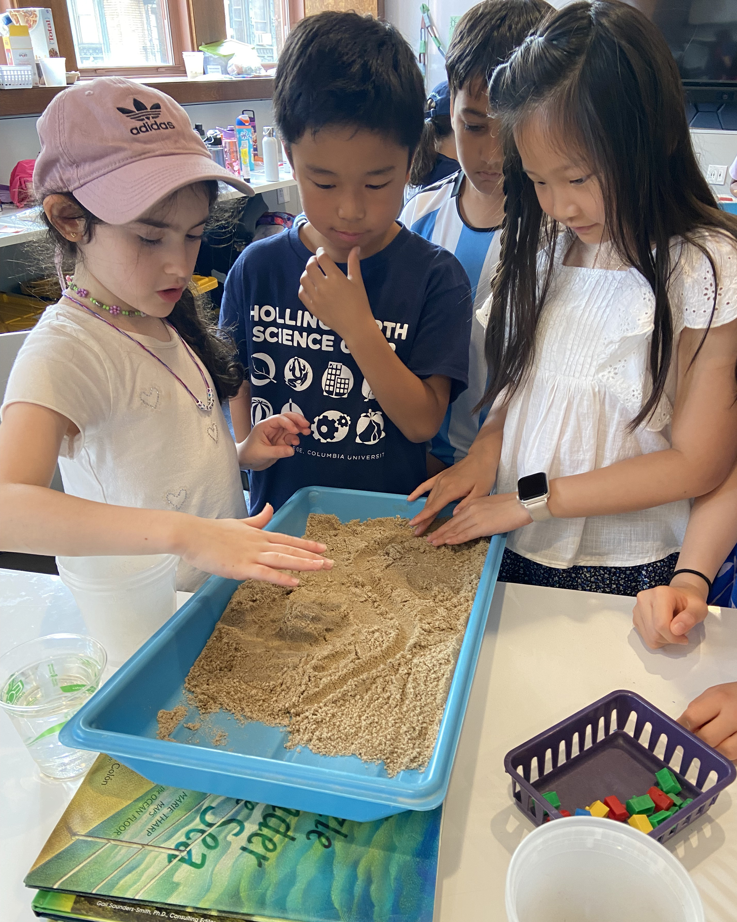 Children gather around a small model of a town set up on an erosion table.