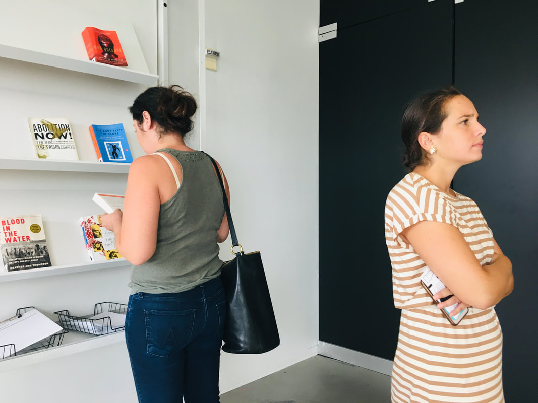 Two people with their backs to one another looking at books on bookshelves