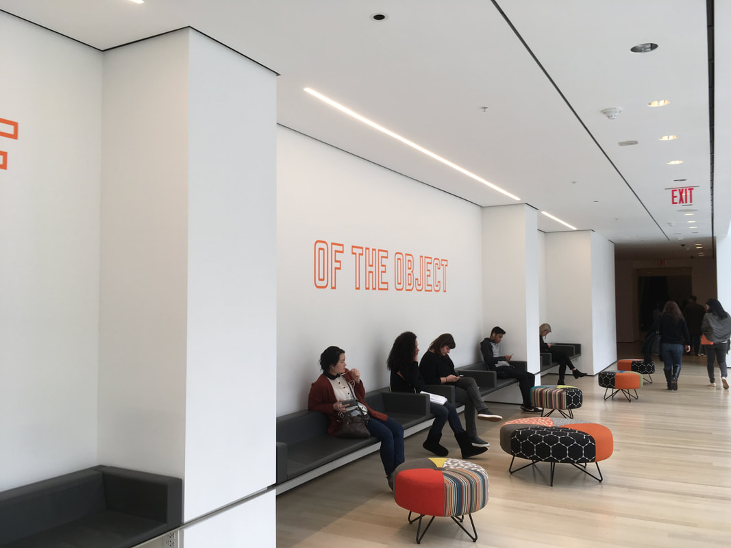 People sitting against white wall with neon orange lettering