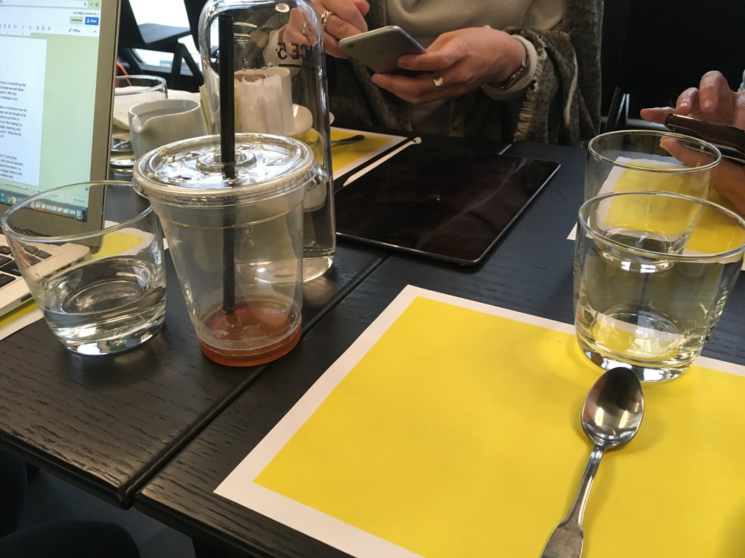 Table with glasses, utensils and plastic cups with dark colored straws