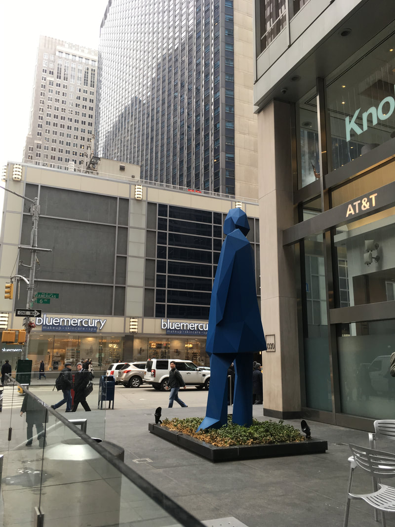Blue geometric sculpture of a person outside near ATM