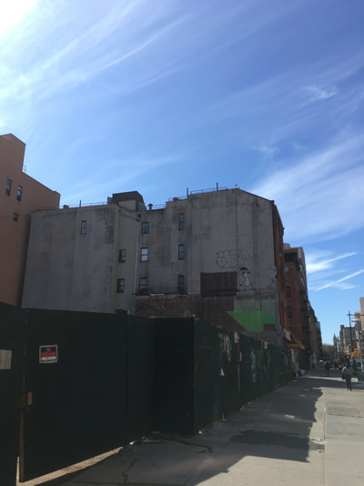 Building with a dark green wooden blockade that has a small  red, black, and white warning sign