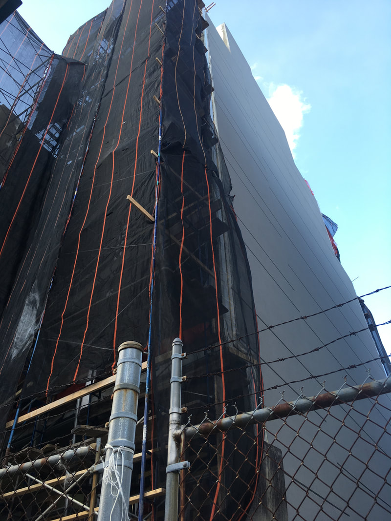 Building with black mesh covering and orange lines moving down the left side of the structure