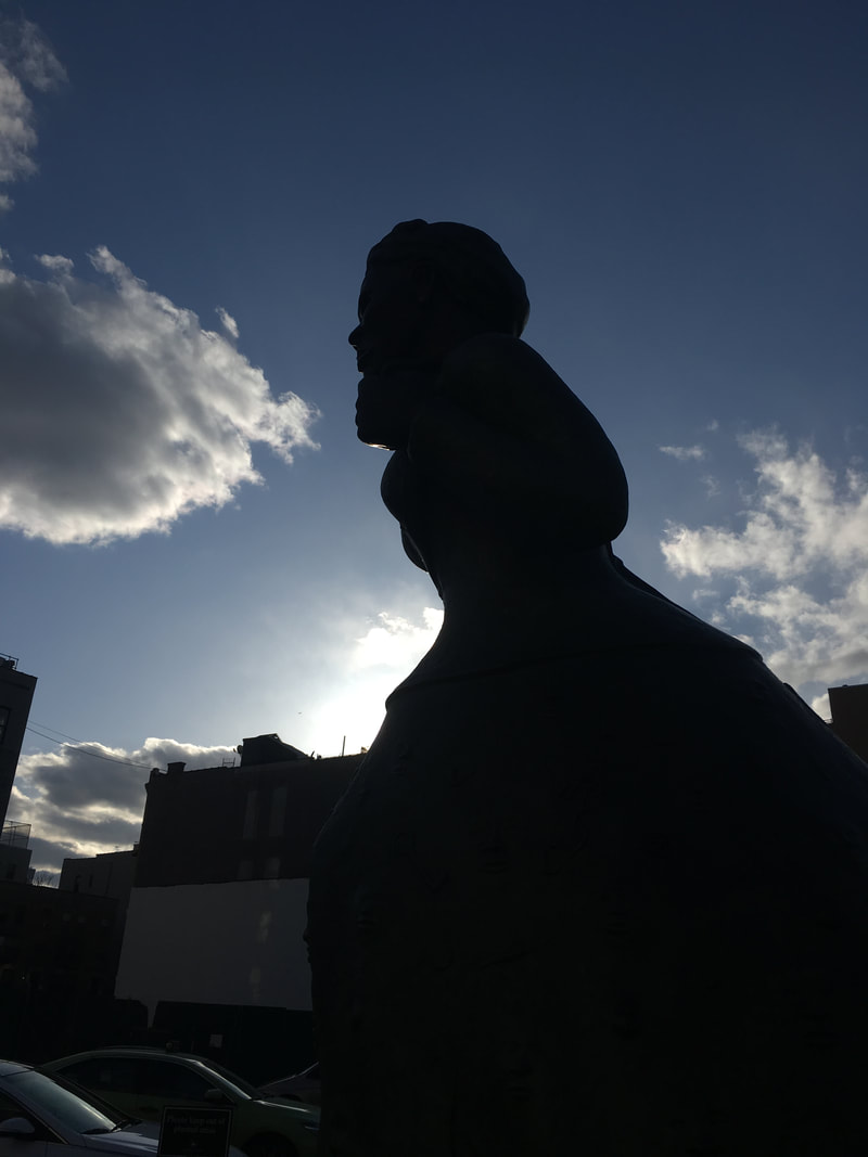 Dark Statueset against a bright blue cloudy sky