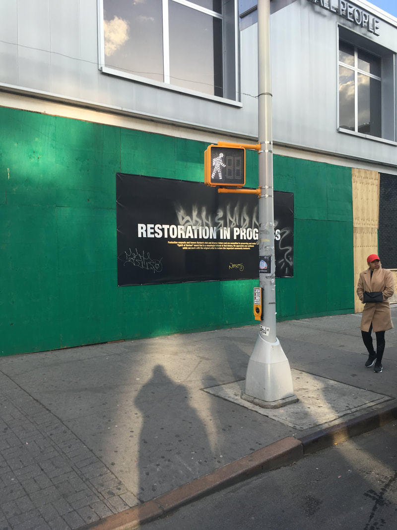 Black Restoration in Process sign with white lettering on a grass green wall