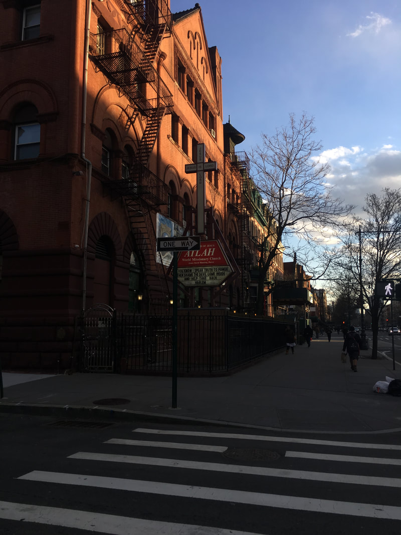 Cross sign signaling a church building in a brownstone walkup near a crosswalk