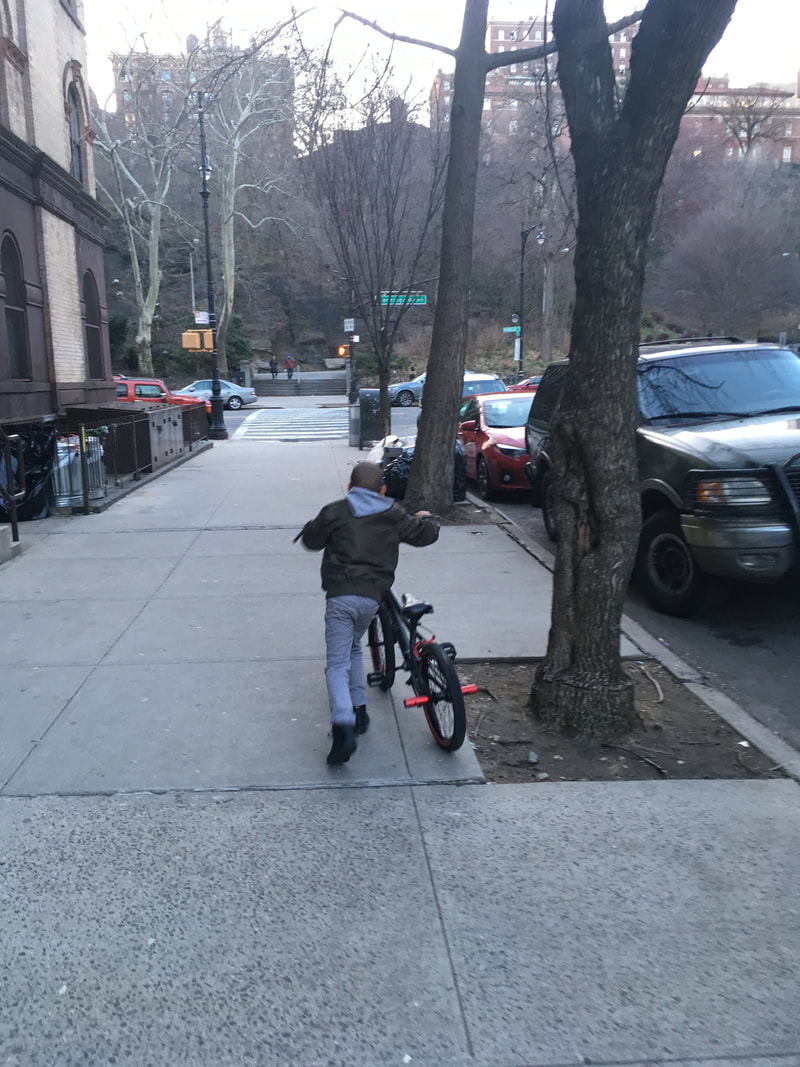 A child rolling their bike down a sidewalk
