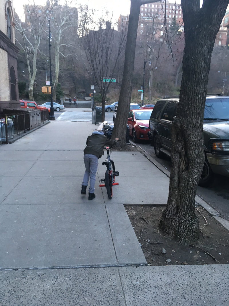 A child pushing their bike down a sidewalk