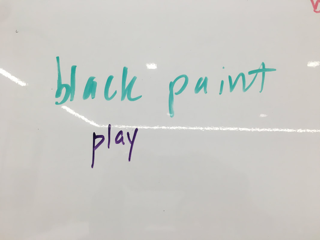 Black paint play written on a whiteboard