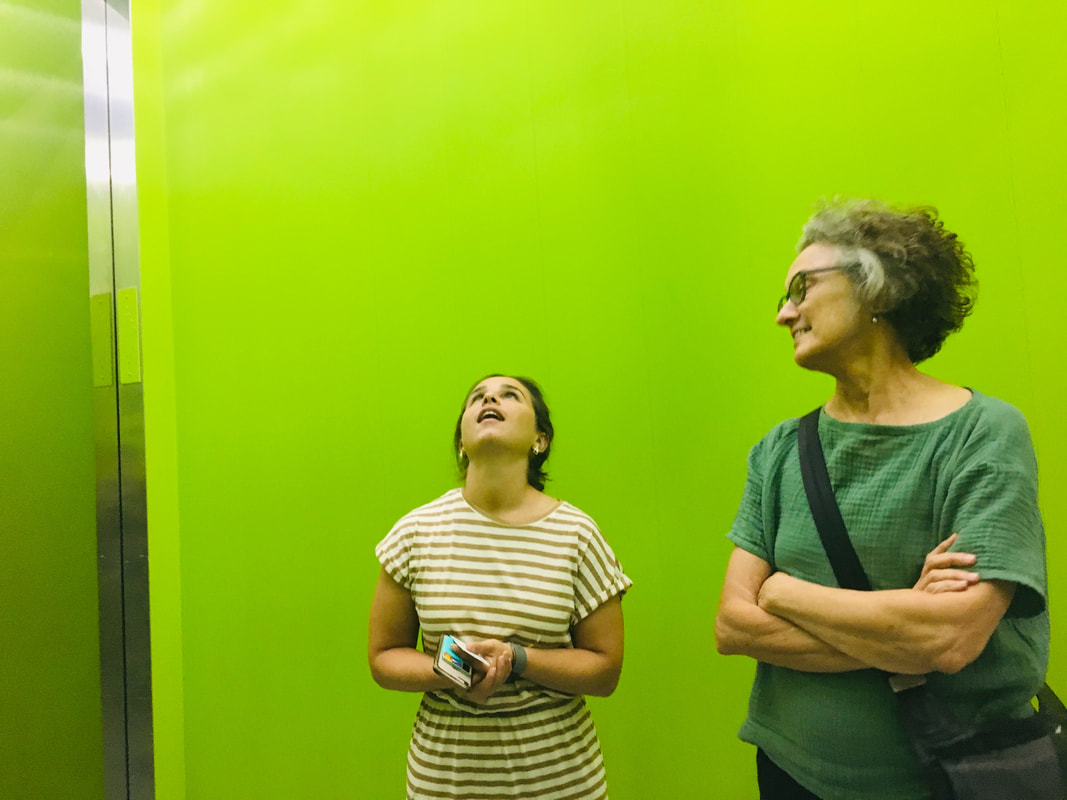 two people standing against lime green background one on the left looking up and the other on the right looking to the left