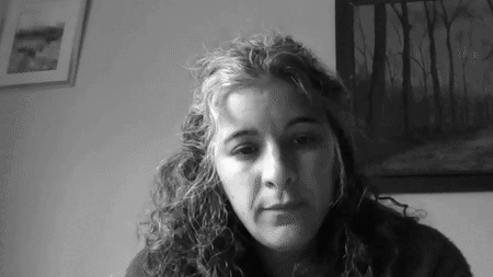A black and white gif of Andrea. Andrea looks at her screen, leaning her face against her hand, then looks off to the side and back to the screen