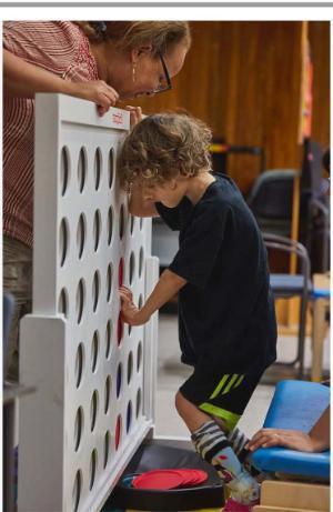 A child braces himself against a large Connect 4 game