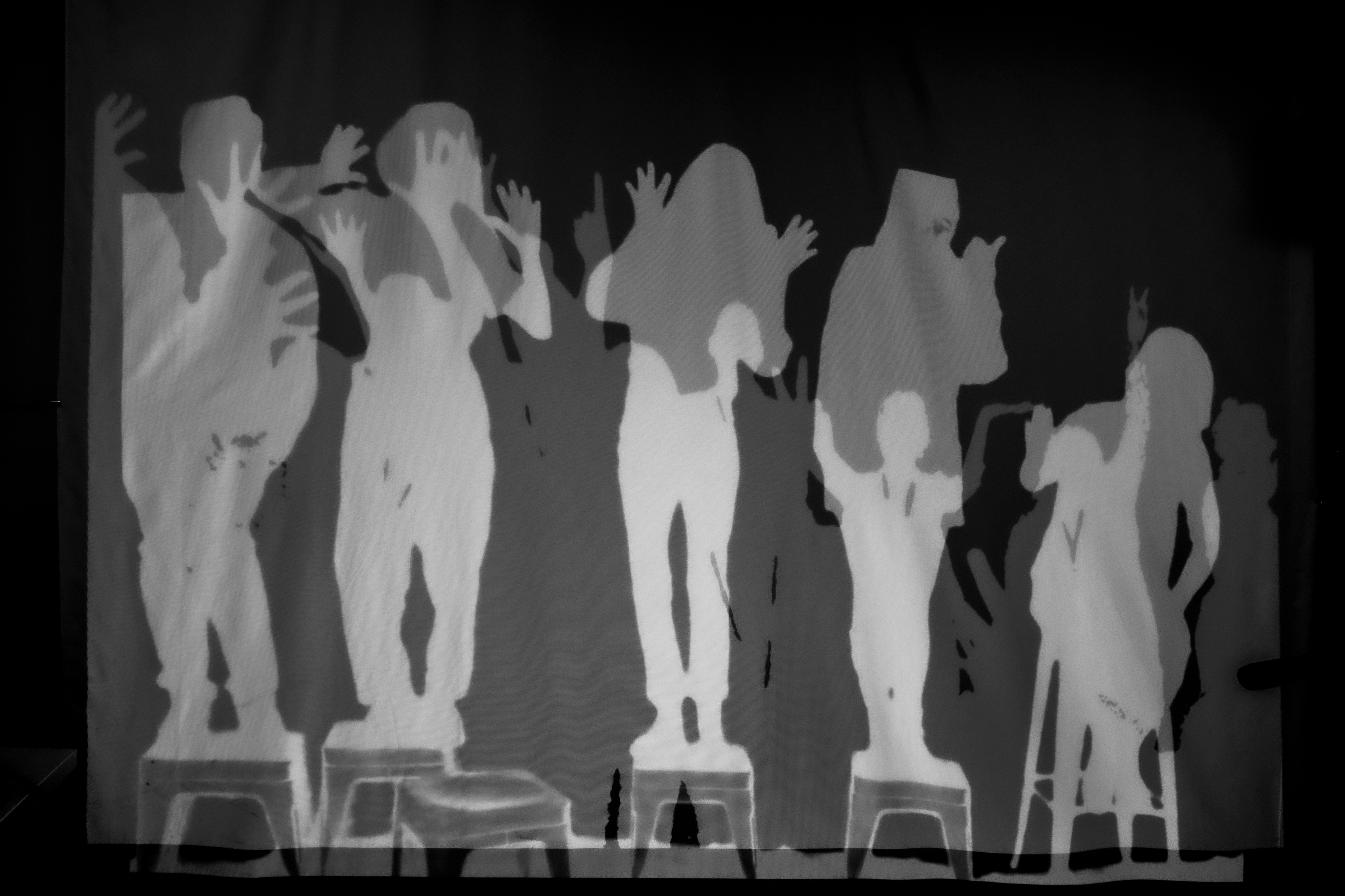 white silhouettes of two groups of people superimposed like shadows on a wall