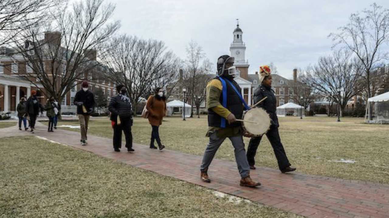 Groovin Griot Season 1 Episode 1 Cover showing people marching. Ritual of Remembrance procession at Johns Hopkins University, led by Urban Foli drummer Menes Yahudah and Kali-Ahset Amen. Photo taken by Will Kirk.
