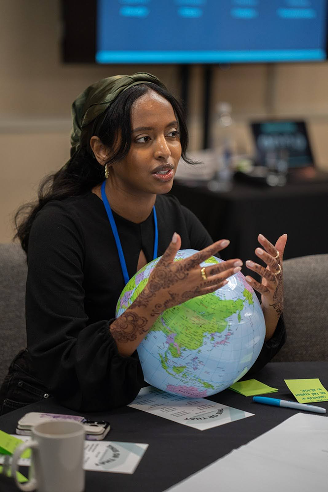 Sabrina Abdalla sits with a globe between her arms. Pictured at a table from waist up.