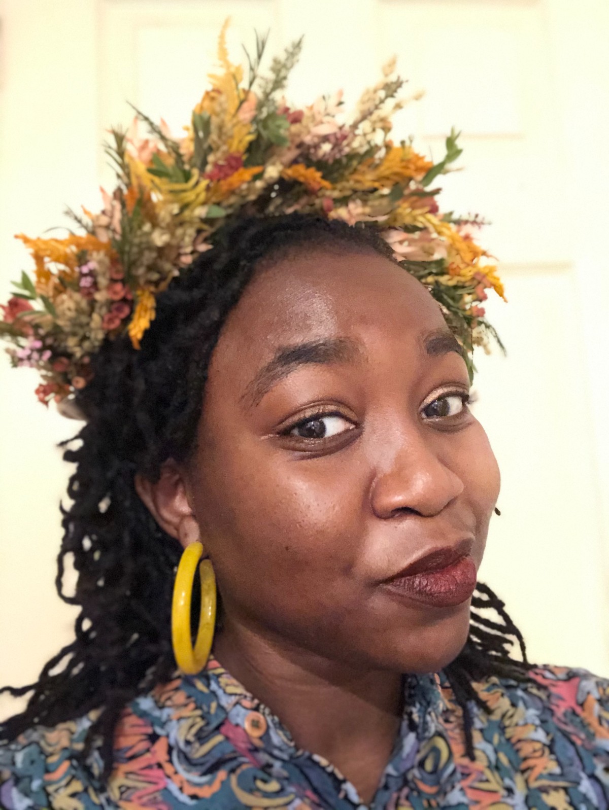 Head shot of Oluwaseun Animashaun wearing botanical wreath