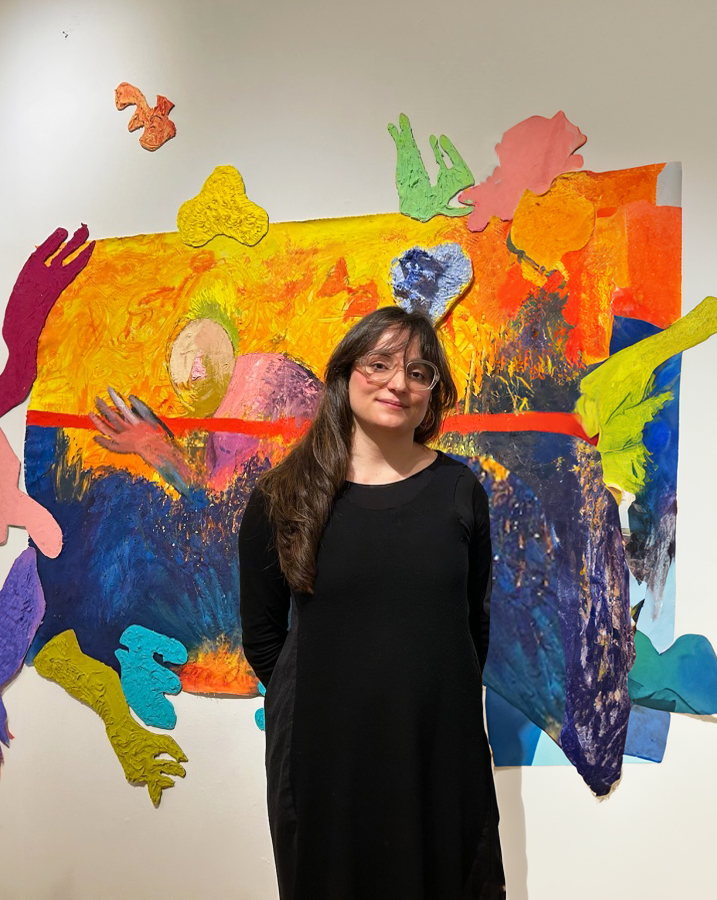 a portrait of an artist with chin-length brown hair in front of an abstract painting