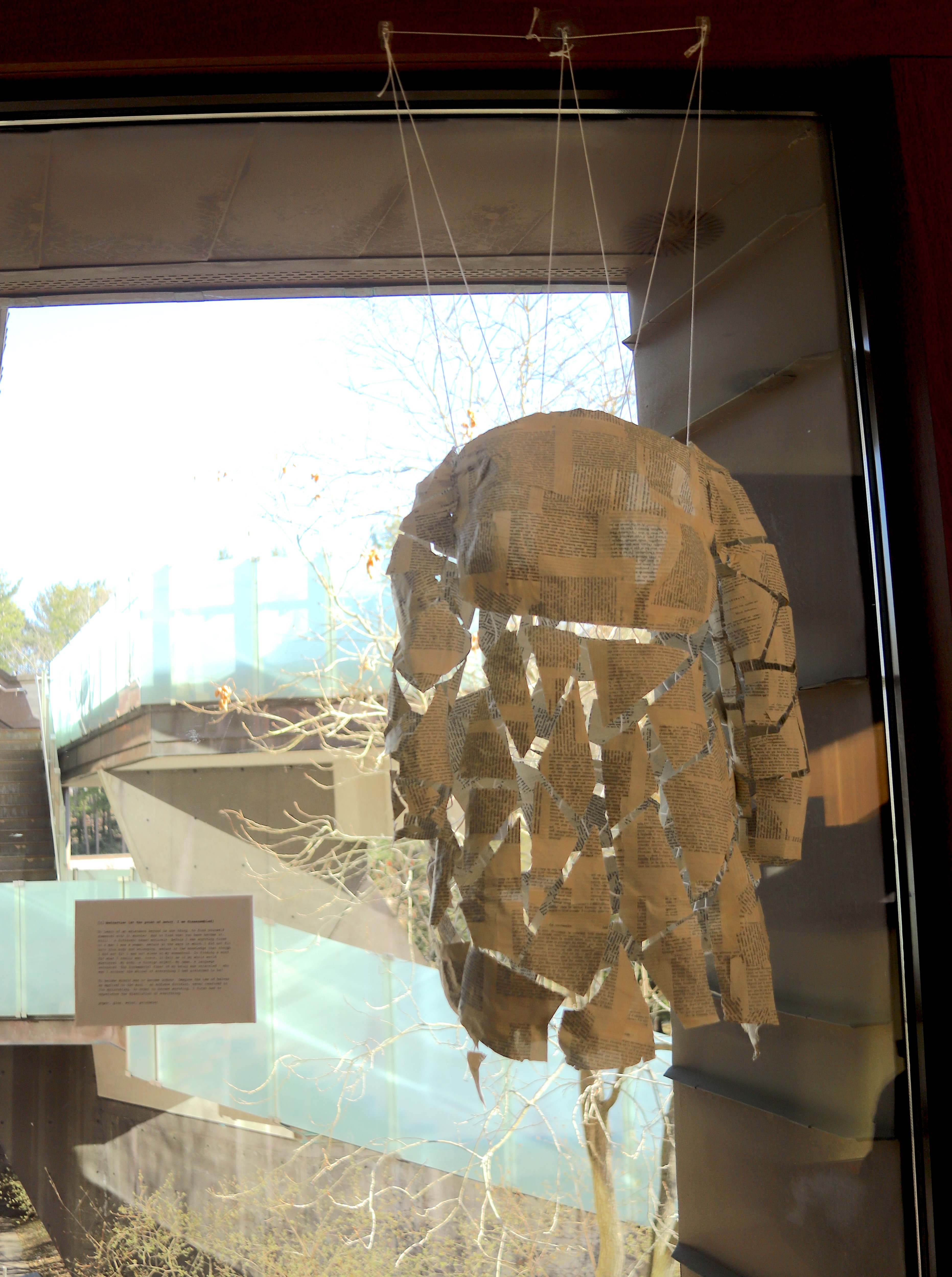 A body form of a young woman made out of paper-mache book pages, fragmented and held together by suspended string