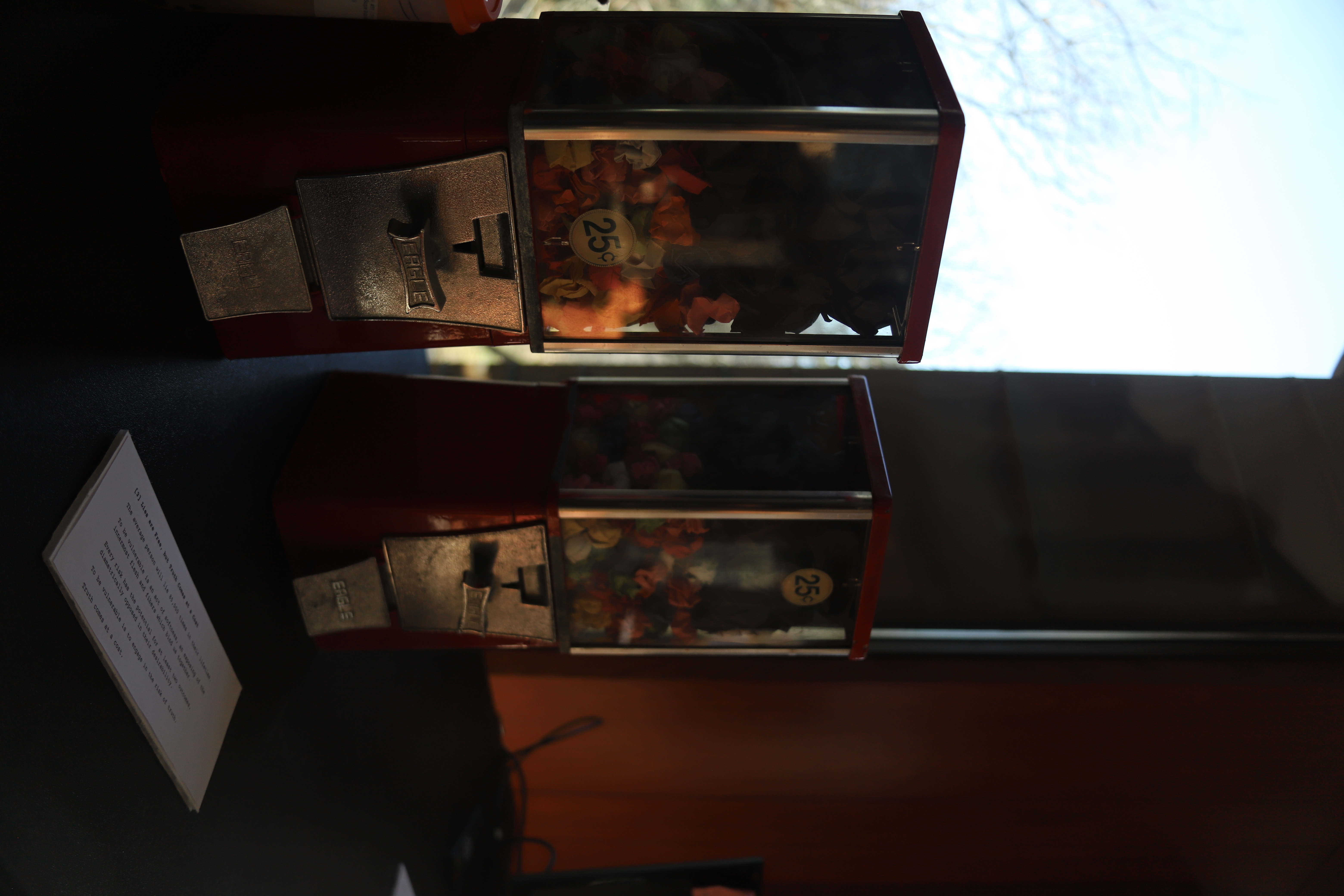 Two coin-operated candy machines, filled with crumpled pieces of colored paper containing written secrets