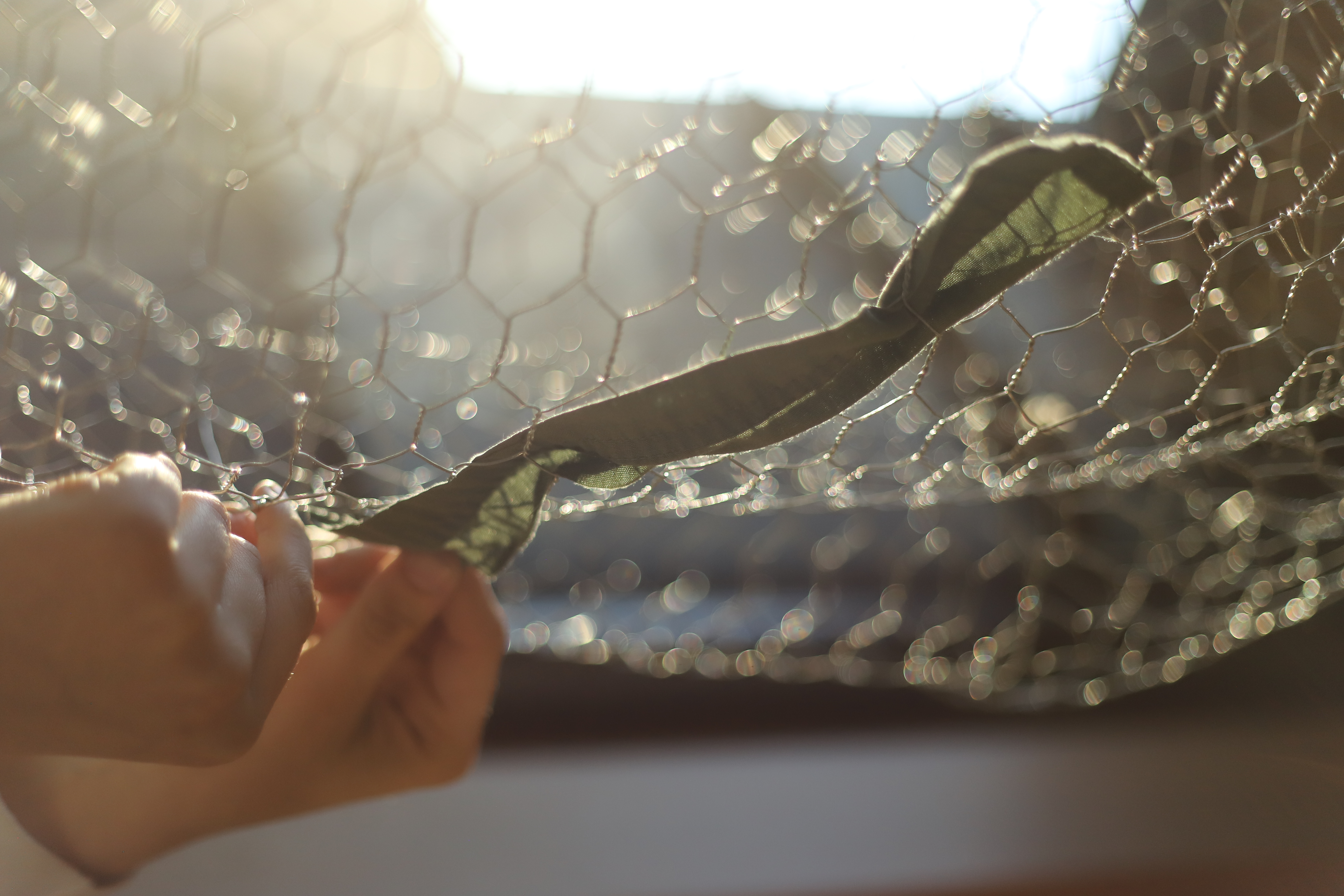 A hand weaving a piece of green cloth through a wireframe body form