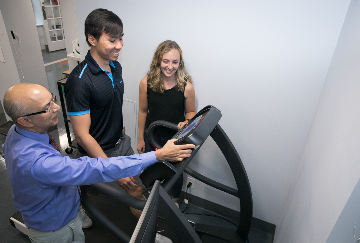 Two PTs work with a person on a treadmill