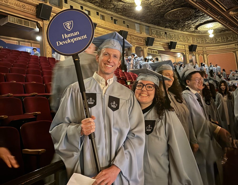 Human Development students smiling, holding a Human Development sign at the 2025 graduation ceremony