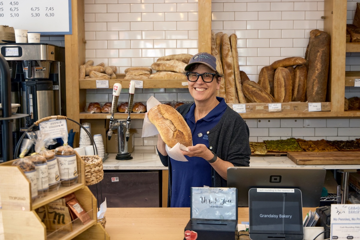 Image of Monica holding a loaf of bread in her bakery