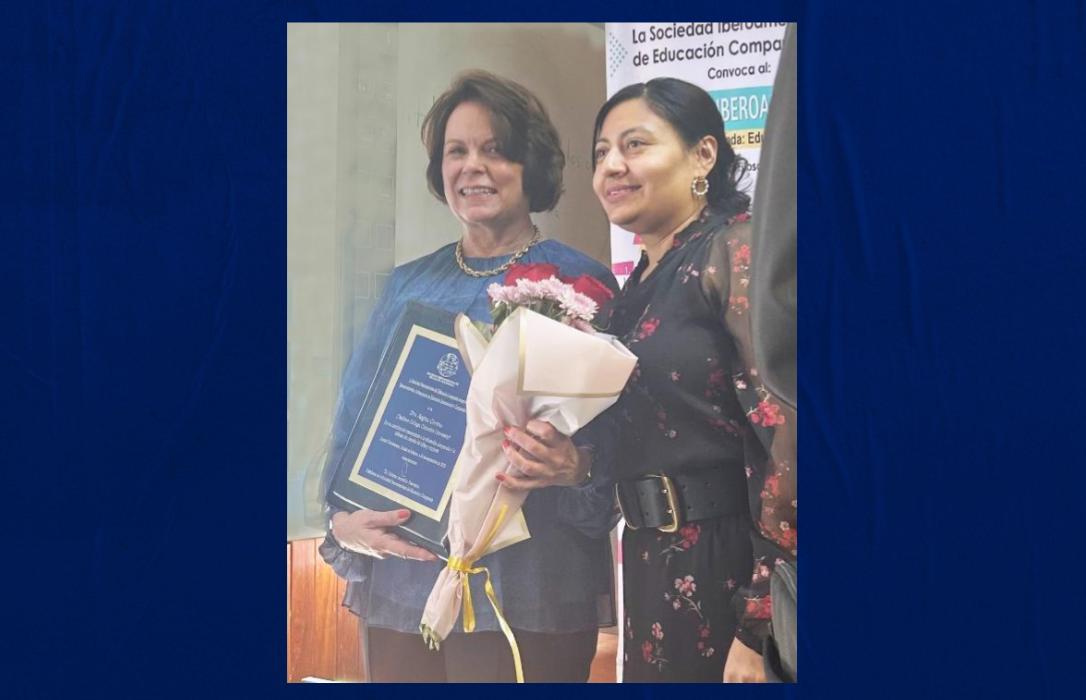Picture of two women holding flowers and receiving an award