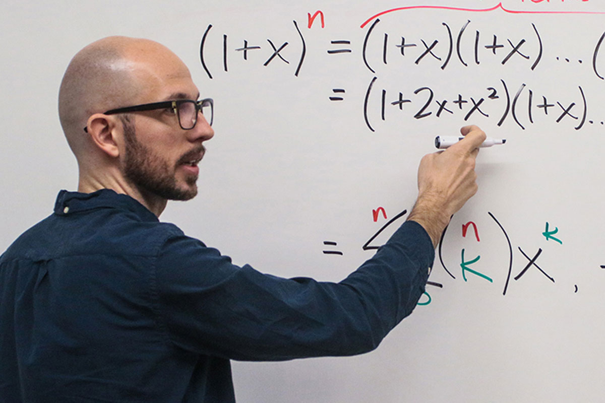Professor Nick Wasserman writes an equation on a white board