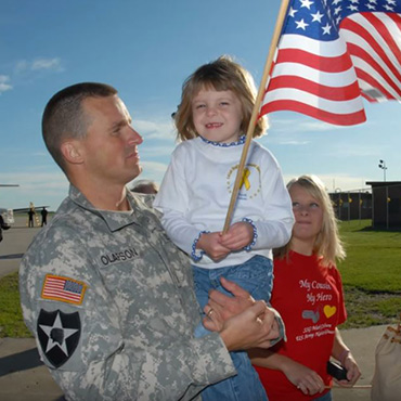A veteran holding his daughter, who is waving the U.S. flag